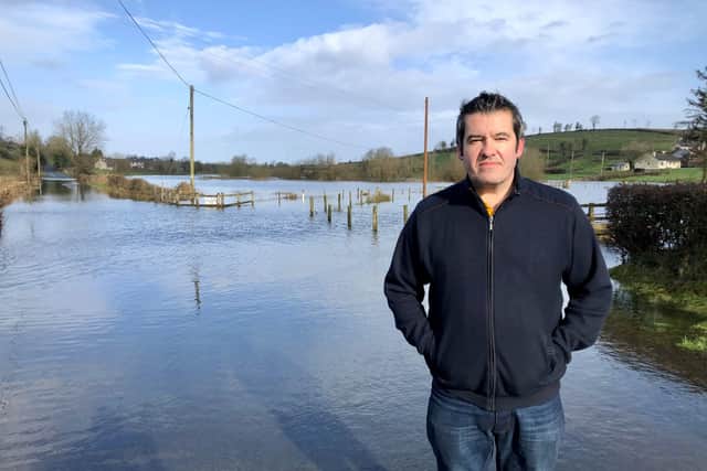 Dessie McKenzie, who lives in Boho and runs the local pub, stands beside one of the flooded roads in the area
