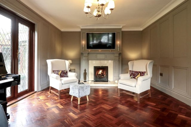 The sitting room, with solid mahogany parquet wood flooring, wooden wall paneling and fireplace (open fire) with wooden surround and marble hearth.
