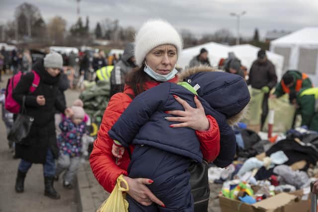 A woman carries her child as she arrives at the Medyka border crossing after fleeing from the Ukraine, in Poland,