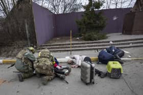 Ukrainian servicemen try to help people wounded, in the town of Irpin, Ukraine, Sunday, March 6, 2022. With the Kremlin's rhetoric growing fiercer and a reprieve from fighting dissolving, Russian troops continued to shell encircled cities and the number of Ukrainians forced from their country grew to over 1.4 million. (AP Photo/Andriy Dubchak)