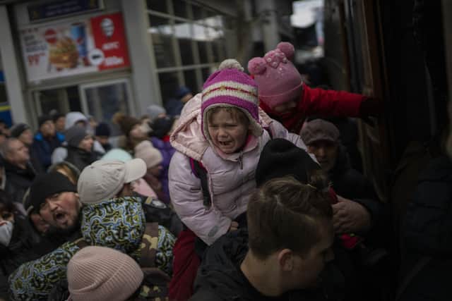 People holding their children struggle to get on a train to Lviv at the Kyiv station, Ukraine, (AP Photo/Emilio Morenatti)