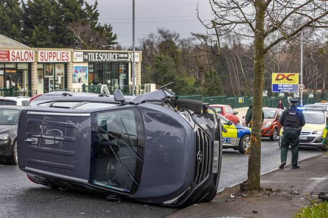 An overturned vehicle on Kennedy Way in west Belfast, with occupants being taken away by ambulance. PA Photo / Liam McBurney/PA Wire