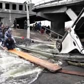 Ukranians flee over a broken highway bridge