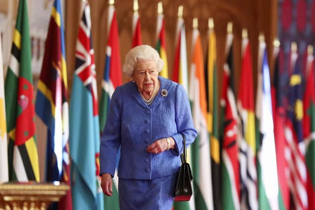 Queen Elizabeth II walks past Commonwealth flags in St George's Hall at Windsor Castle , to mark Commonwealth Day 2021
