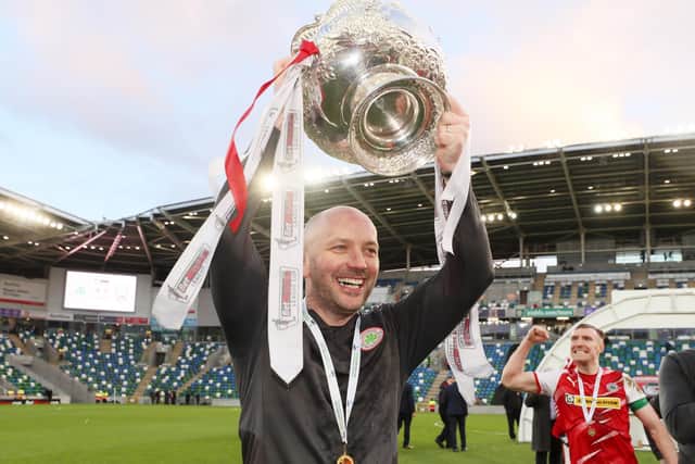Cliftonville boss Paddy McLaughlin shows off the trophy to Reds supporters