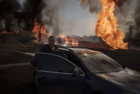 A man enters a car to leave the area of a fire, following a Russian attack in Kharkiv, Ukraine.