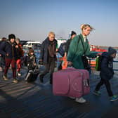 Refugees from Ukraine walk on the jetty after arriving by ferry at the Romanian-Ukrainian border point Isaccea-Orlivka on March 24, 2022. (Photo by Daniel MIHAILESCU / AFP) (Photo by DANIEL MIHAILESCU/AFP via Getty Images)