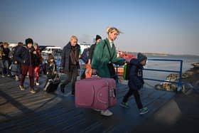 Refugees from Ukraine walk on the jetty after arriving by ferry at the Romanian-Ukrainian border point Isaccea-Orlivka on March 24, 2022. (Photo by Daniel MIHAILESCU / AFP) (Photo by DANIEL MIHAILESCU/AFP via Getty Images)