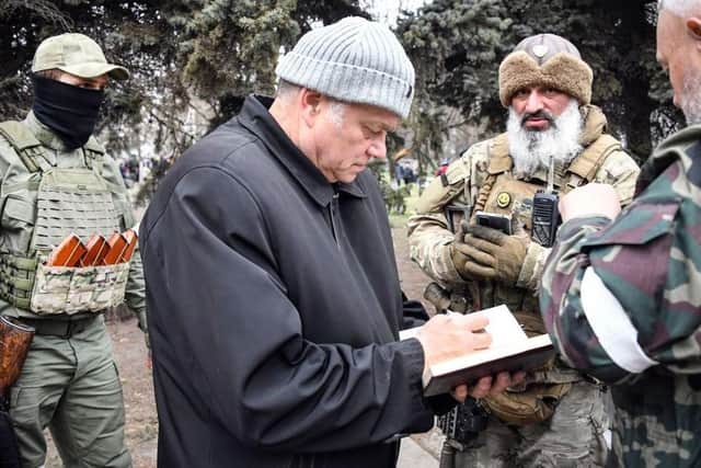 Konstantin Ivashchenko, former CEO of the Azovmash steel plant and newly appointed pro-Russian mayor of Mariupol writes notes flanked by his bodyguards, in Mariupol on April 12, 2022. * This picture was taken during a trip organized by the Russian military.*