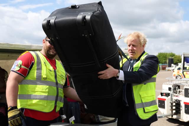 Prime Minister Boris Johnson loads baggages on a conveyor belt for an air-plane, on the tarmac of Southampton airport during a visit to the Eastleigh constituency, while on the local elections campaign trail. Picture date: Wednesday May 4, 2022.