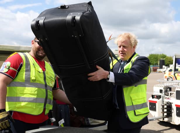 Prime Minister Boris Johnson loads baggages on a conveyor belt for an air-plane, on the tarmac of Southampton airport during a visit to the Eastleigh constituency, while on the local elections campaign trail. Picture date: Wednesday May 4, 2022.