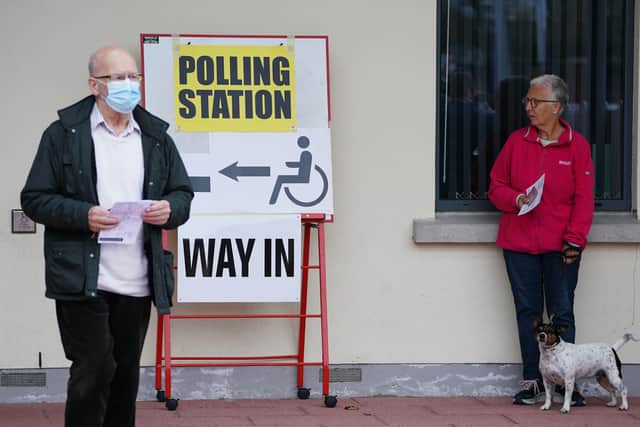 A woman with a dog outside the polling station at Dromore Central Primary School in Dromore, Co Down, as people cast their vote in the 2022 NI Assembly election. Picture: Brian Lawless/PA Wire