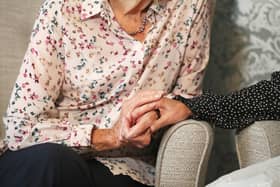 A care home resident holding hands with her daughter. One in four people with dementia experience symptoms for more than two years before they are diagnosed, according to new research