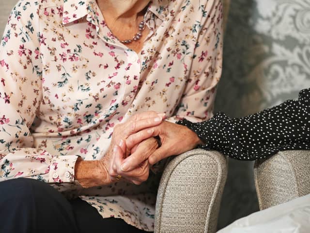 A care home resident holding hands with her daughter. One in four people with dementia experience symptoms for more than two years before they are diagnosed, according to new research