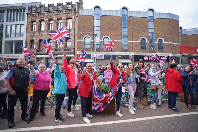 Members of the public in Belfast city centre wave flags and enjoy the spectacle of the centenary parade. Photo: Niall Carson/PA Wire