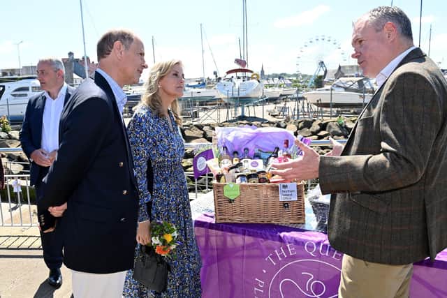 The Earl and Countess of Wessex talk to the NIO minister Conor Burns MP, beside a hamper of Northern Ireland produce, on the pier in Bangor on Saturday. In the background is the marina and a temporary ferris wheel. The royal visitors were cheered by a large crowd on their visit to the seaside city. Jubilee celebrations here follow another big event, when people finally got to mark NI’s centenary.. 
Photo by Stephen Hamilton / Press Eye