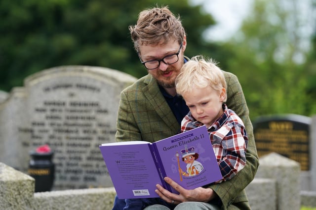 Robert Henning reads a story for his son Arthur (3) as they attend a picnic at St. Bartholomew's Parish Church, Newry, as part of the Big Jubilee Lunch as celebrations continue across Northern Ireland for the Queen's Platinum Jubilee. Picture date: Sunday June 5, 2022.