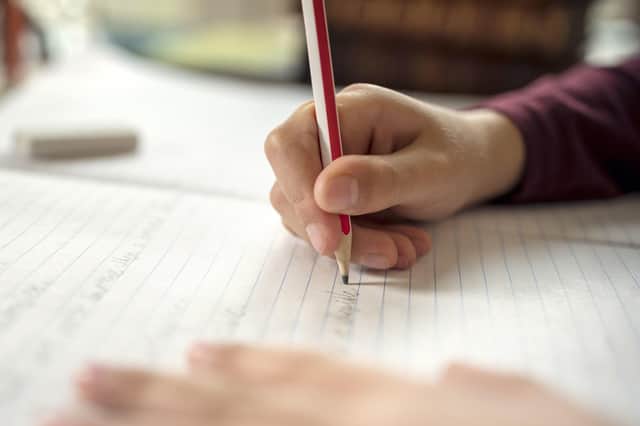A generic photo of a child writing in a school book.