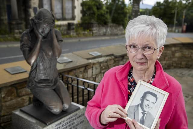Anne Bradley, whose husband Arthur Hone known as Artie Hone, was one of nine killed in the Claudy bombings in 1972, stands holding an image of Artie, at the Claudy bombing memorial statue created by sculptor Elizabeth McLaughlin.