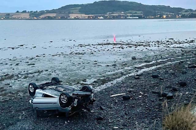 Handout photo issued by PSNI Ards and North Down of a car that had crashed off a coastal road and landed on its roof on the shore of Strangford Lough. The driver of the vehicle was found close to the scene of the incident on the Portaferry Road in the early hours of Saturday.