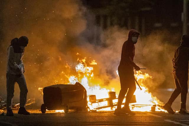 People stand next to a fire in a street in Belfast during further unrest. (Photo: PA)