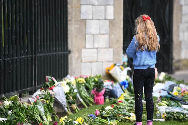 A young girl looks at flowers at Cambridge Gate at Windsor Castle, Berkshire, following the announcement of the death of the Duke of Edinburgh at the age of 99.