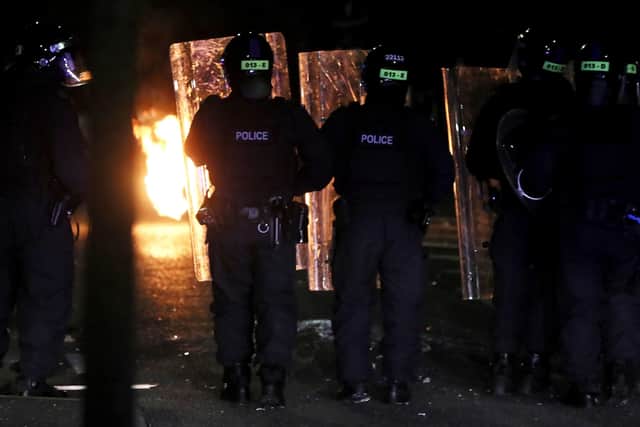 PSNI officers look on after a Loyalist rioter threw a petrol bomb in the Tigers Bay Area of North Belfast during further unrest in Northern Ireland. Picture date: Friday April 9, 2021