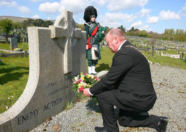 Lord Mayor of Belfast Alderman Frank McCoubrey laying a wreath at Milltown Cemetery while piper Matthew Wilson plays Abide With Me