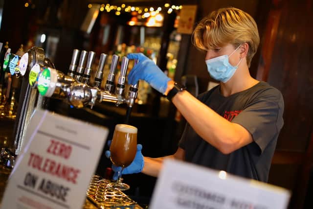 Bar staff in PPE pour drinks at the reopening a Wetherspoons pub