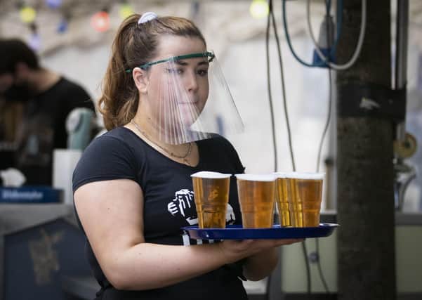 A member of staff serves drinks in the beer garden at the Bier Halle, Glasgow, where outdoor areas have already reopened to the public