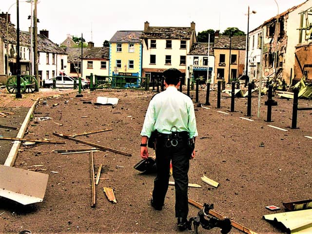 A policeman walks through the aftermath of an INLA car bomb attack against the village of Newtownhamilton, Co Armagh, on June 24, 1998; the explosives detonated just as RUC officers were clearing people away from the area, wounding at least three people and wrecking the village’s centre
