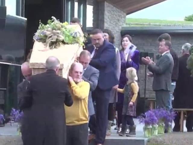 Family and friends clap along to the music in celebration of the life of Denis Lynn as his remains are taken on one last tour of his business empire in Co Down today.