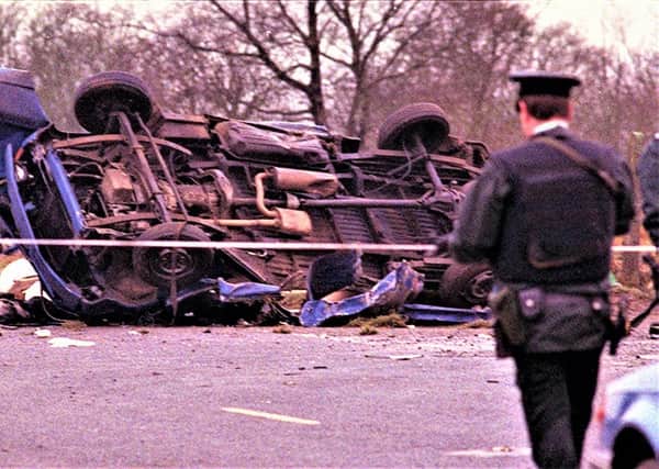 A policeman stands guard by a destroyed vehicle carrying 14 Protestant workmen in the Teebane area of Co Tyrone, 1992. The IRA attack killed eight