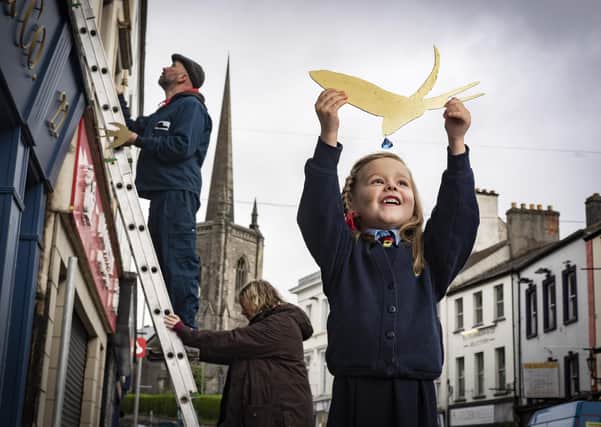 Five year old Thea Johnston, Enniskillen Integrated Primary helps artist Simon Carman and Helen Sharp as they begin the installation150 little swallows in gold leaf in and around Enniskillen centre. Picture by Brian Morrison.