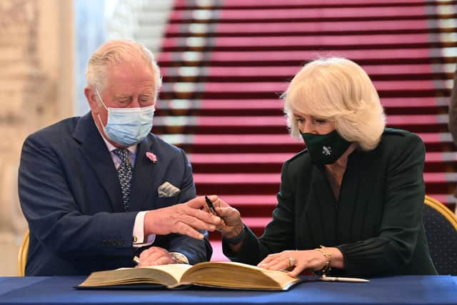 The Prince of Wales and the Duchess of Cornwall signing the visitor's book during a visit to Belfast City Hall in Donegall Square, Belfast