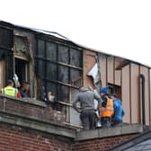 Workers clear debris around the Malone Exchange on the Lisburn Road, Belfast, where there was a fire in the building's penthouse earlier on Tuesday. Over 40 firefighters attended the scene. Picture date: Tuesday May 18, 2021.