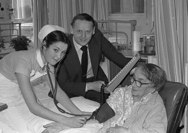 Minister of State Michael Alison lends a helping hand to student nurse Diane McCartney of Belfast as she takes the blood pressure of patient Mrs Elizabeth Allington, during the minister's visit to Belfast City Hospital in April 1980. Picture: News Letter archives
