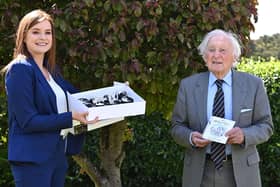 Randal Black celebrates reaching 100 with a gift from Charlotte McClean, manager of the Old Inn, Crawfordsburn, where he is a regular customer. The inn presented him with a £100 hotel voucher and birthday cupcakes to celebrate his milestone.