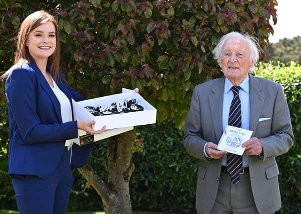 Randal Black celebrates reaching 100 with a gift from Charlotte McClean, manager of the Old Inn, Crawfordsburn, where he is a regular customer. The inn presented him with a £100 hotel voucher and birthday cupcakes to celebrate his milestone.