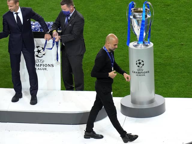 Manchester City manager Pep Guardiola with the runners up medal as he walks past the Champions League trophy at Estadio do Dragao in Porto.