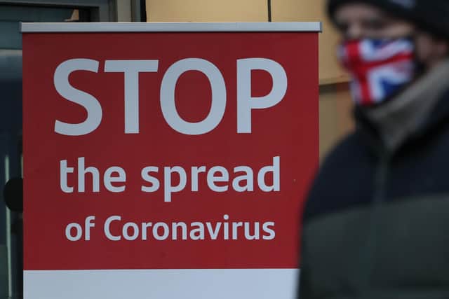 A man wearing a face mask walks past a coronavirus advice sign. Photo credit: Andrew Milligan/PA Wire