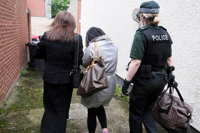 A woman, centre, is lead away by police ,after they raided a house during an operation to rescue a number of women