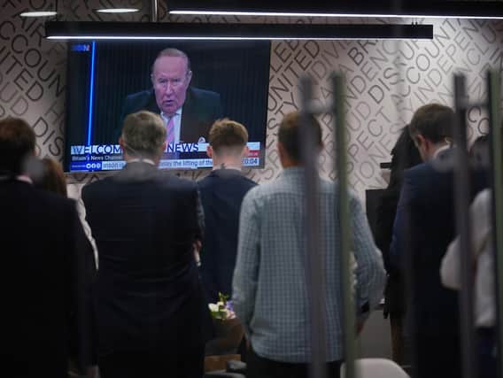 Staff in the green room watching a television screen showing presenter Andrew Neil broadcast from a studio, during the launch event for new TV channel GB News at The Point in Paddington, London