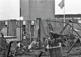 A tattered Union flag flies above the remains of a Magherafelt Army base in early 1991, while a trio of men survey the damage from a 500lb (220kg) IRA proxy bomb. The base had been used by the UDR; there were no fatalities