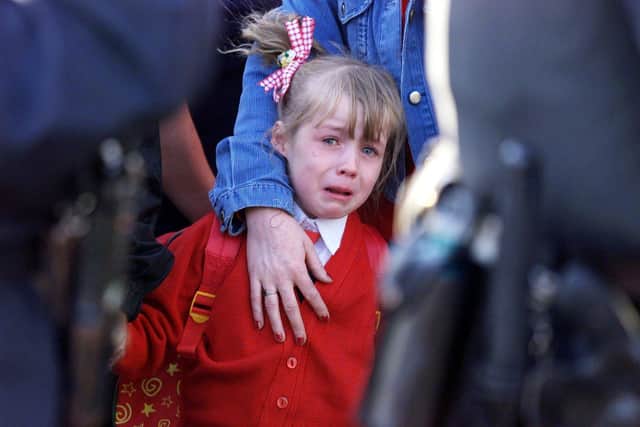 Alice-Lee Bunting, 5, seen through a RUC human corden, being comforted by her mother, as she is escorted to Holy Cross school, north Belfast.
