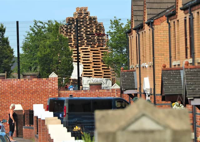 A woman looks at the loyalist bonfire, built in the loyalist Tiger's Bay area, from nationalist New Lodge area in north Belfast