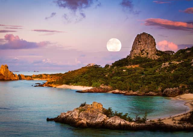 The moon over a coastal landscape, Okinawa, Japan.