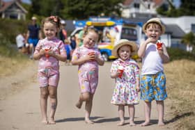 (left to right) Twins Bella and Layla Hughes (4) with Annie Shepherd (2) and her brother Jude Shepherd (5) eating screwball ice creams at Helen's Bay beach in County Down, Northern Ireland. Picture date: Tuesday July 20 2021.