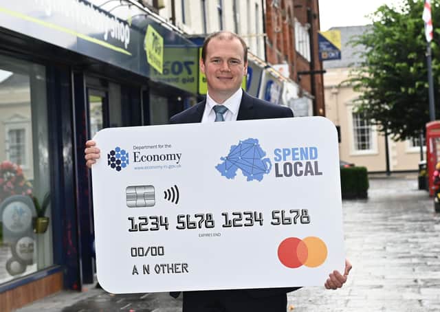 Economy Minister Gordon Lyons with the £100 voucher logo