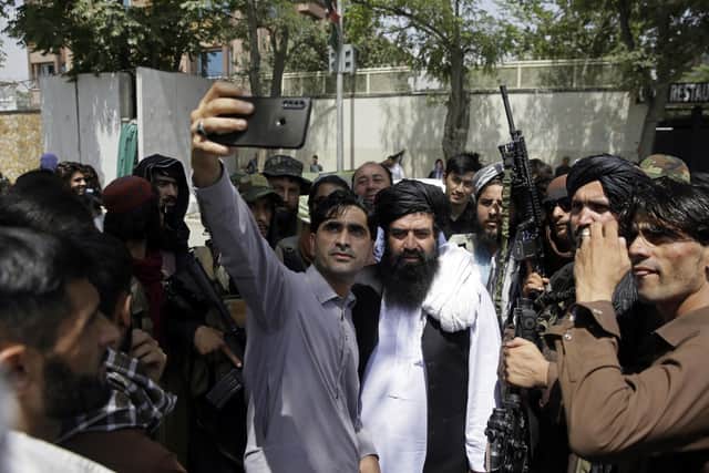An Afghan takes a selfie with Taliban fighters on patrol in Kabul today, Thursday, Aug. 19, 2021 (AP Photo/Rahmat Gul)